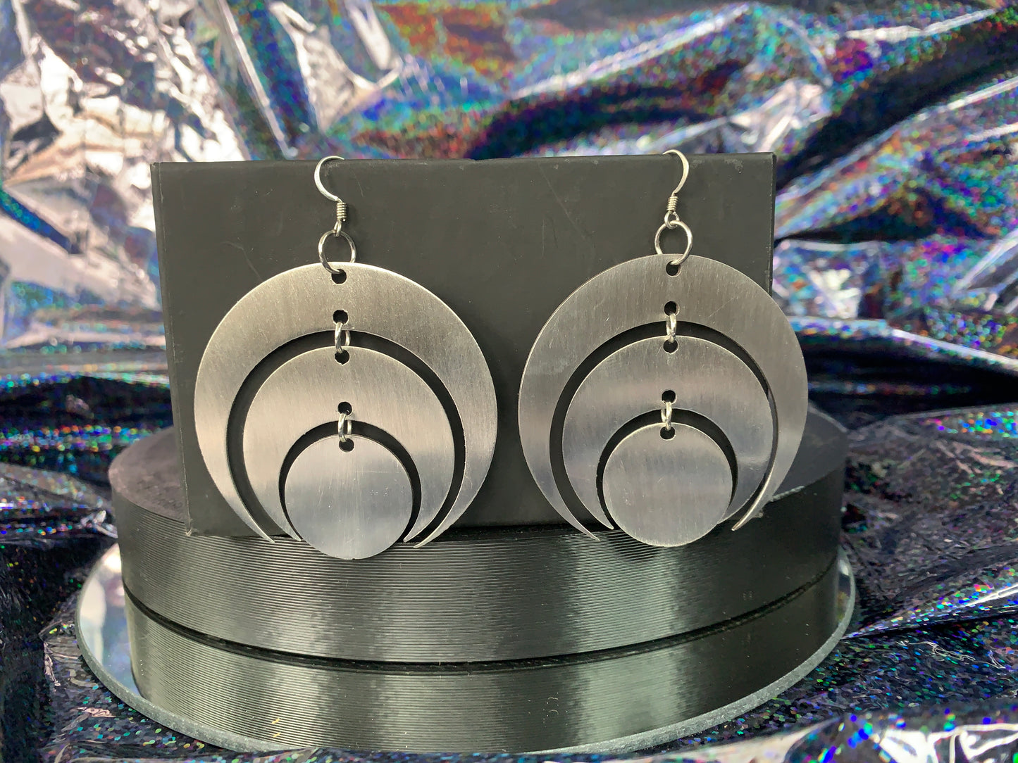 A pair of stainless steel laser cut earrings made into tiered inverted crescent shapes.