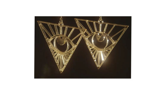 Laser cut gold mirrored acrylic inverted triangle  earrings featuring an eye with sunbeams within the triangle.
